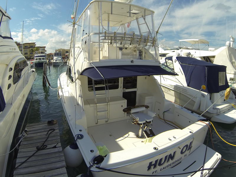 Vista de proa del sportfisher Riviera 43 atracado en Cancún con silla de pelea en el cockpit y flybridge bajo cielo azul