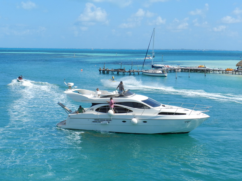 Yate Azimut Flybridge 50 pies navegando aguas turquesas del Caribe frente al muelle de Isla Mujeres, renta de yates de lujo en Cancún