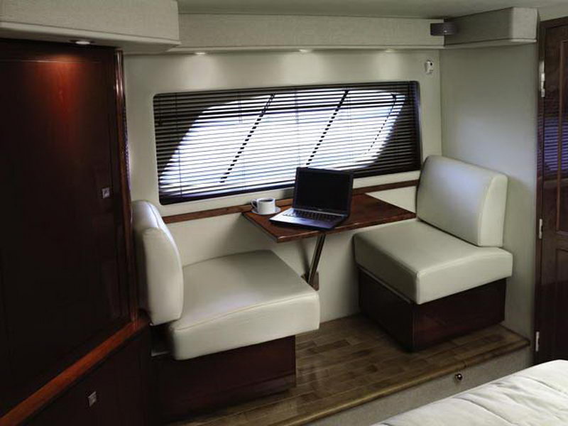 Dinette area aboard Sea Ray 55 ft yacht rental with fold-down teak table, white leather seating and portlight window