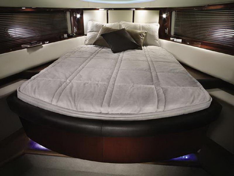 Master stateroom of Sea Ray 55 ft luxury yacht charter with circular bed, dark leather frame and ambient mood lighting
