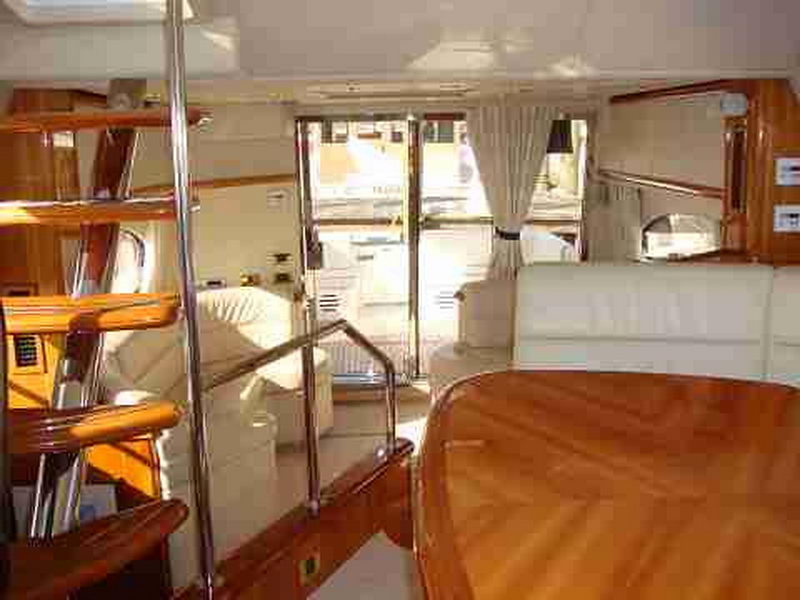 Below-deck interior of Sunseeker Manhattan 56 ft luxury yacht with stateroom passage, cream curtains and polished wood table
