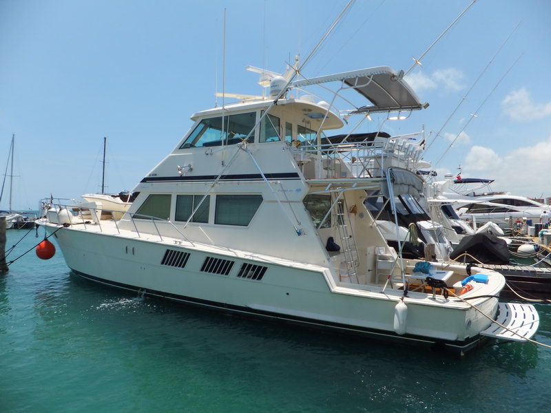 Hatteras 66 ft deep-sea fishing charter boat exterior profile at tropical marina with bridge deck and trolling outriggers Cancun