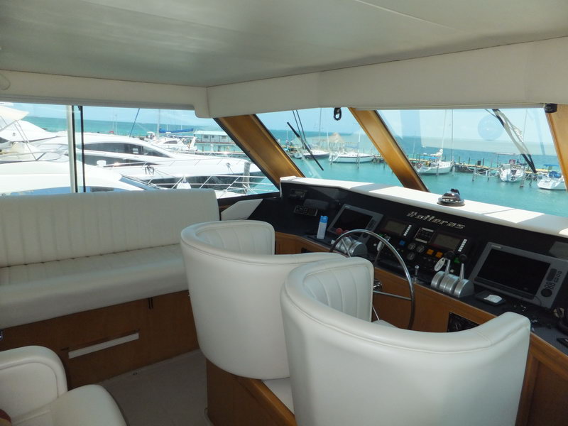 Hatteras 66 ft helm station with Hatteras navigation electronics, captain chairs and panoramic view of Cancun marina