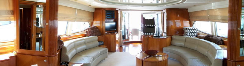 Panoramic main salon of Azimut 100 ft mega yacht showing cream leather sofas, cherry wood paneling, and flatscreen TV