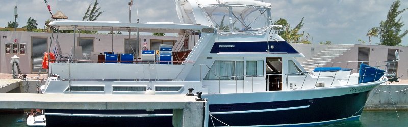 Blue-hulled 58 ft Sandralyn Jefferson motor yacht docked at a Cancun marina with flybridge and covered aft deck ready for private charters