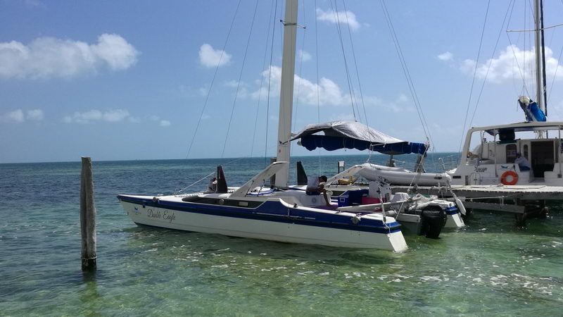 Catamarán Dude Eagle 30 pies amarrado en aguas turquesas cristalinas en Isla Mujeres, charter de vela privado para grupos pequeños desde Cancún
