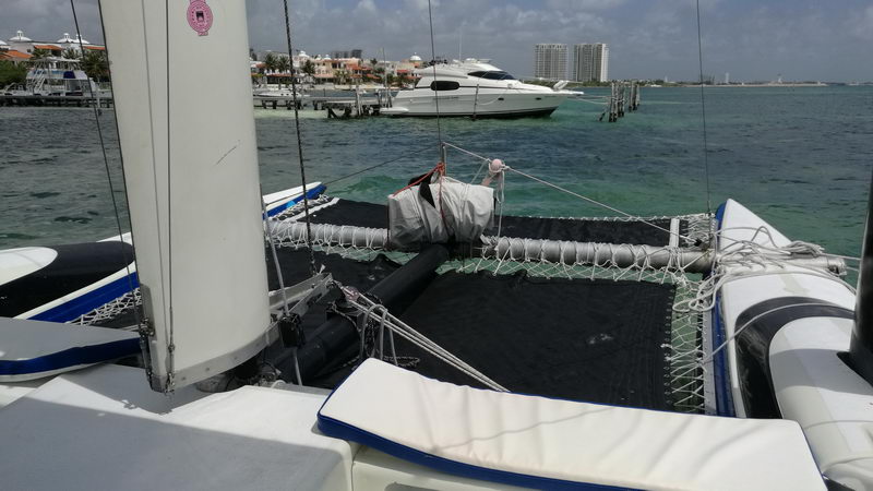 Red de trampolín y proa del Catamarán Eagle Jazz con Zona Hotelera de Cancún al fondo, charter privado de vela 30 pies Isla Mujeres