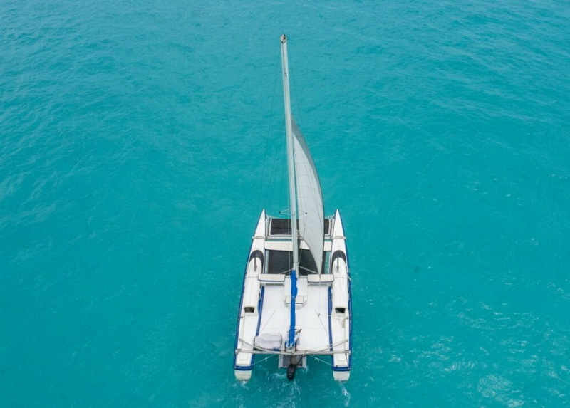 Vista aérea cenital del Catamarán Eagle Jazz navegando sobre el Caribe turquesa brillante cerca de Cancún, charter privado 30 pies hasta 20 personas