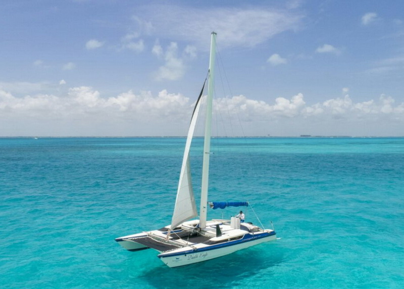 Catamarán Eagle Jazz navegando a vela plena sobre el mar Caribe turquesa cerca de Cancún, charter privado Isla Mujeres familias y grupos pequeños