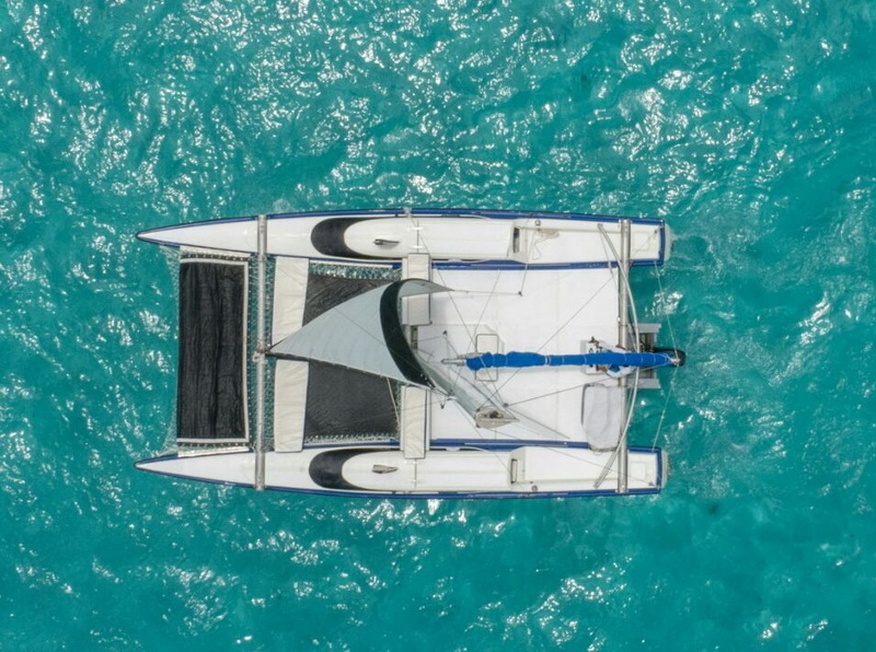 Vista aérea superior del trimarán Catamarán Eagle Jazz amarrado en el Caribe turquesa, charter privado de vela Cancún grupos íntimos