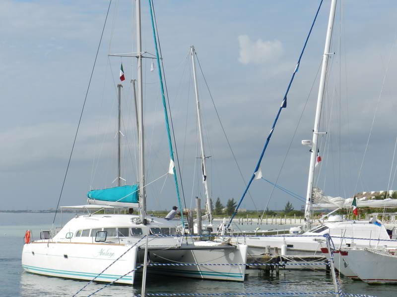 Lagoon 40 ft catamaran docked among sailboats at Maroma marina near Playa del Carmen, Mexican flag flying over the turquoise Riviera Maya