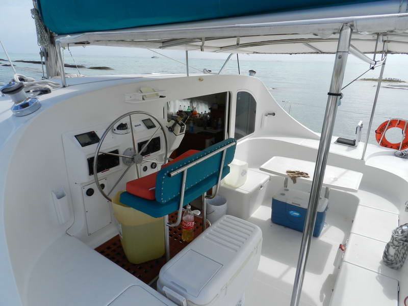 Open helm and shaded cockpit of the Maroma Lagoon catamaran with coolers and cold drinks, ready for a Playa del Carmen day charter on turquoise water