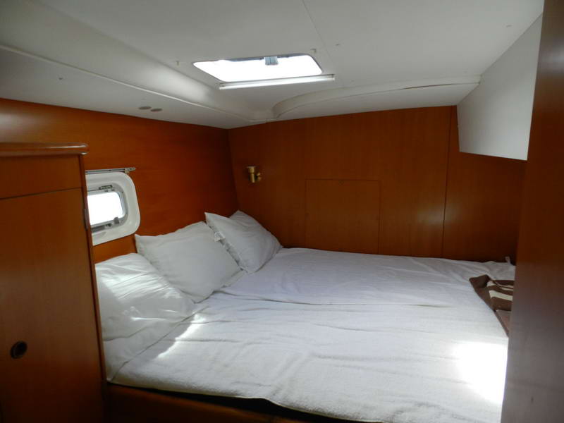 Interior double cabin with warm wood paneling and white linens aboard the Lagoon catamaran, offering shaded rest during Riviera Maya snorkeling tours