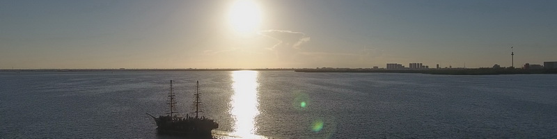 Silhouette of the Columbus Spanish galleon replica sailing Cancun's Nichupte Lagoon at golden sunset with the hotel zone skyline behind
