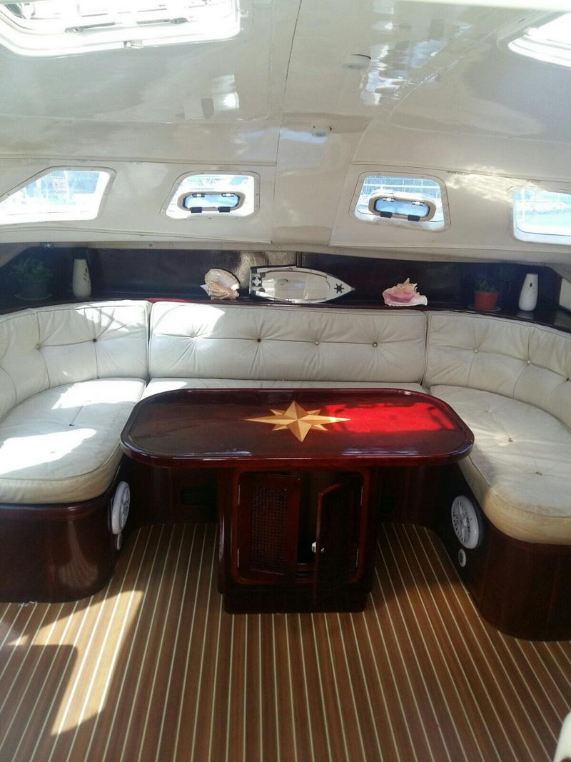 Interior salon of the Lavezzi 42 catamaran with white leather seating and a varnished wood table with compass-star inlay
