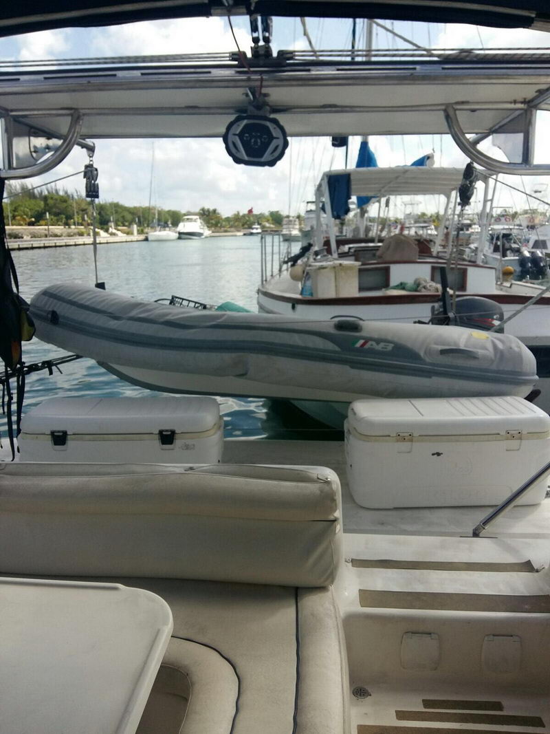 Aft deck of the Cozumel sailing catamaran with dinghy on davits, coolers and sun seating overlooking the marina