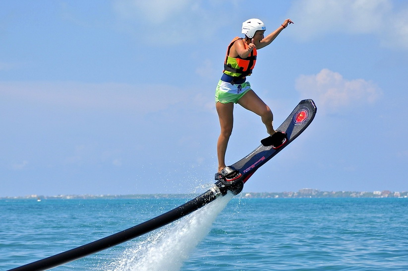 Rider deslizándose sobre un hoverboard impulsado por agua sobre el Caribe turquesa brillante frente a Cancún con casco y chaleco salvavidas