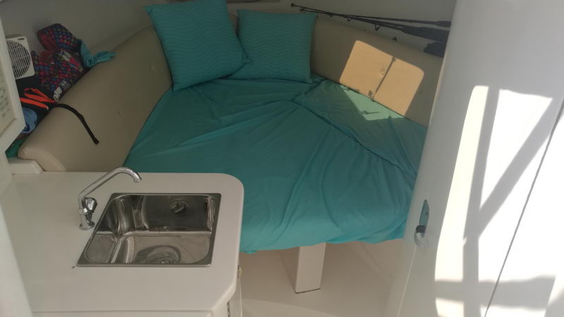 Cozy forward cabin of the Intrepid 32 with a turquoise V-berth, sink and galley for overnight or full-day fishing comfort