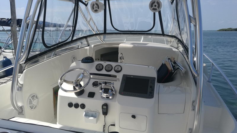 Helm station of the Intrepid 32 with steering wheel, fishfinder, radio and gauges under the shaded hardtop, Cancun fishing boat