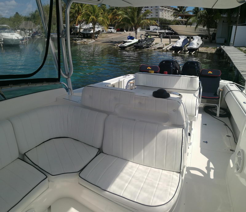 Spacious white cushioned cockpit and seating of the Intrepid 32 sport boat at a Cancun canal dock lined with palms