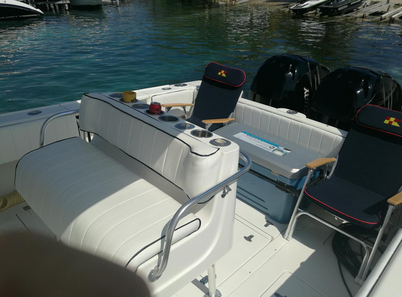 Aft deck of the Intrepid 32 with padded seating, cooler and twin black outboards ready for a Cancun fishing charter