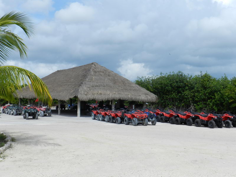 Rows of red ATVs parked beside a thatched palapa at the 