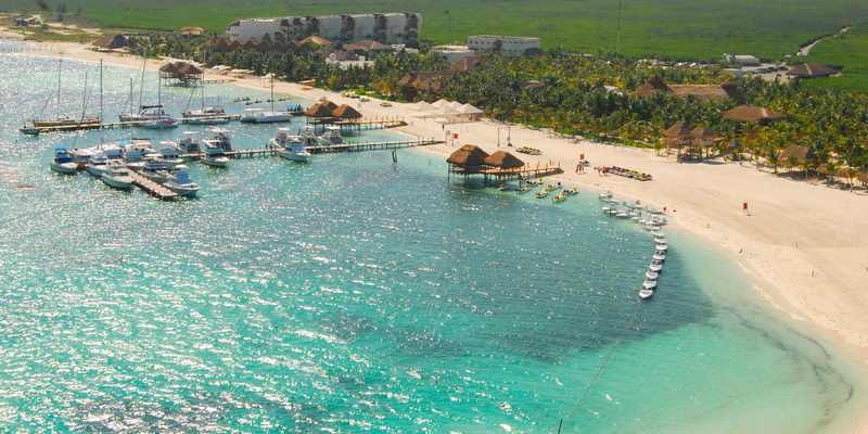 Aerial view of Marina Maroma with catamarans and boats moored at the piers along the white sand beach and turquoise Caribbean