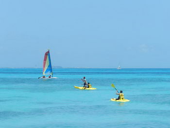 Guests paddling sea kayaks on the calm turquoise water along the Cancun coastline
