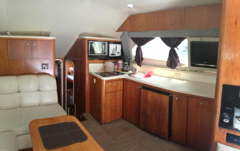 Cocina del yate Luhrs de 38 pies con gabinetes de madera, estufa, microondas y sala, Puerto Aventuras Riviera Maya