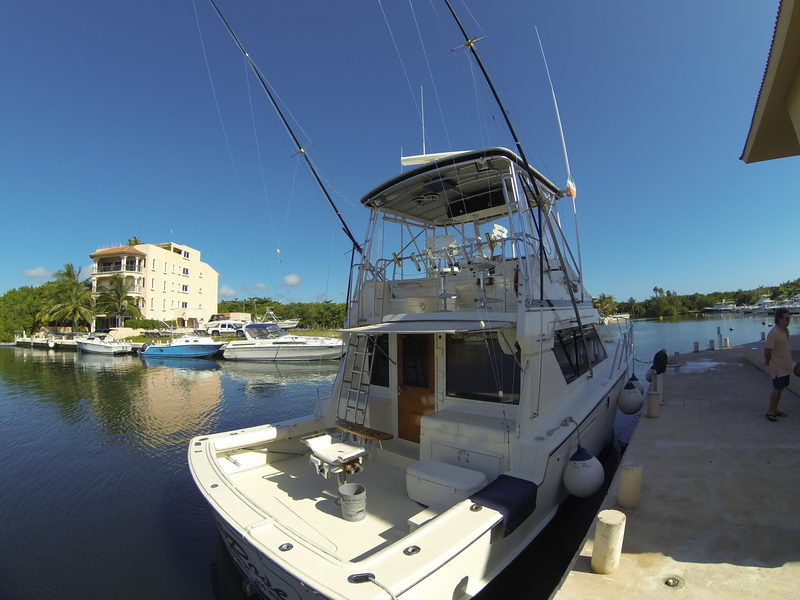 45 ft Hatteras sport fishing yacht rental moored in calm Puerto Aventuras marina canal under blue Caribbean sky Riviera Maya