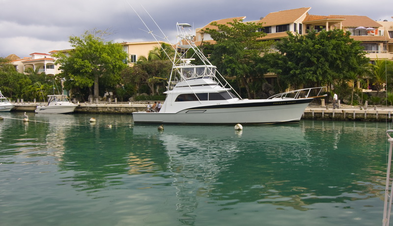 50 ft Hatteras sportfishing yacht with flybridge and tuna tower moored in calm Puerto Aventuras marina Riviera Maya