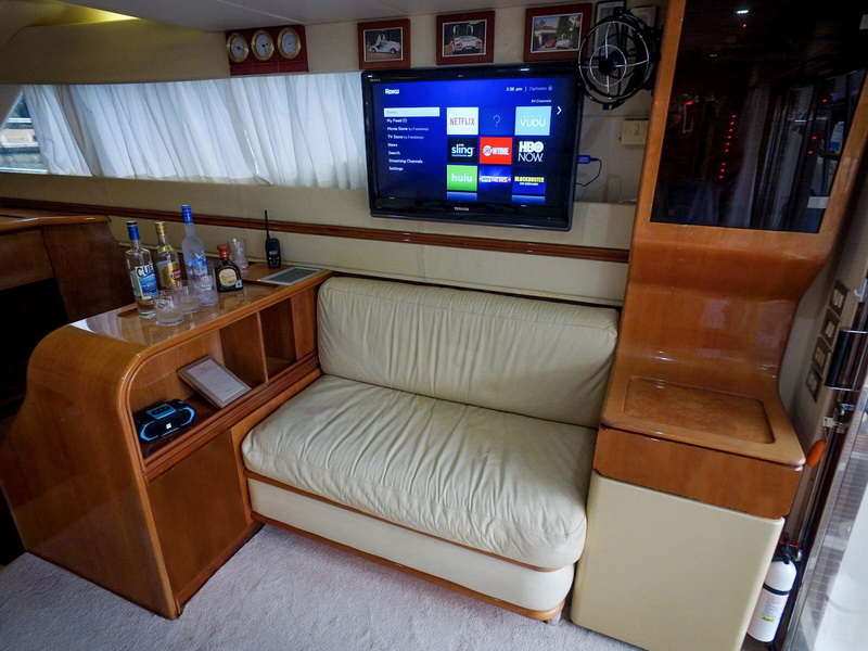 Salon lounge with leather sofa, flat-screen TV and bar aboard 48 ft Azimut yacht charter Riviera Maya