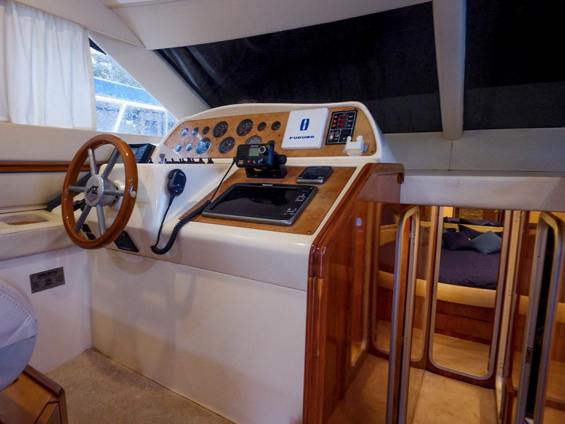 Interior helm station with wooden wheel and Furuno electronics on 48 ft Azimut luxury yacht Puerto Aventuras