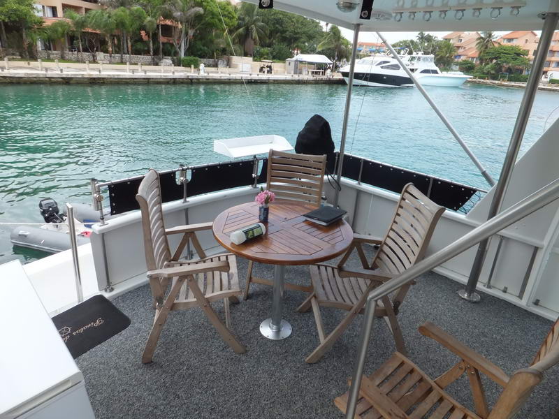 Covered aft deck of the Piratas De Tejas with round teak table and folding wooden deck chairs
