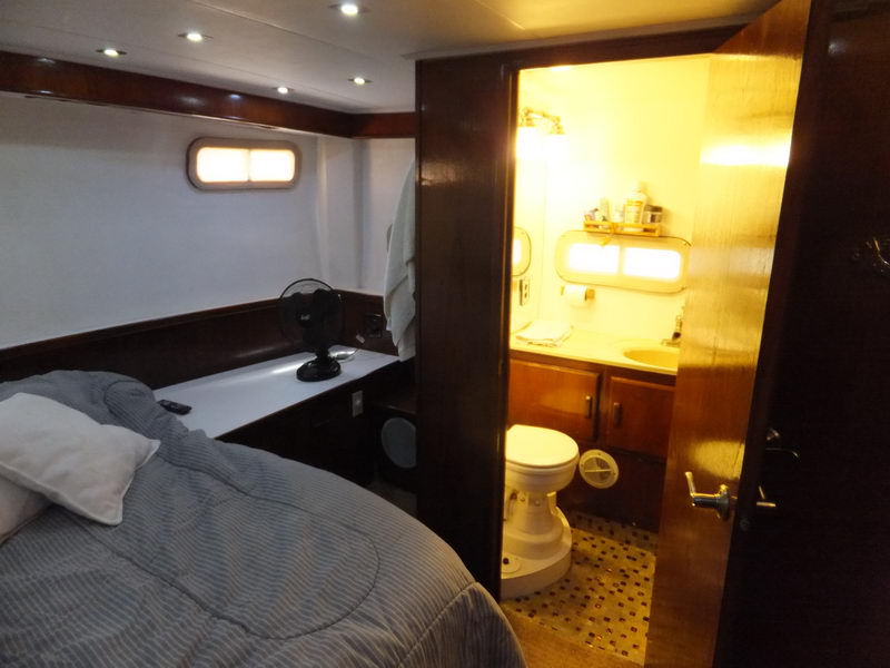 Guest cabin with double bed and blue-striped bedding, wood vanity and adjoining ensuite