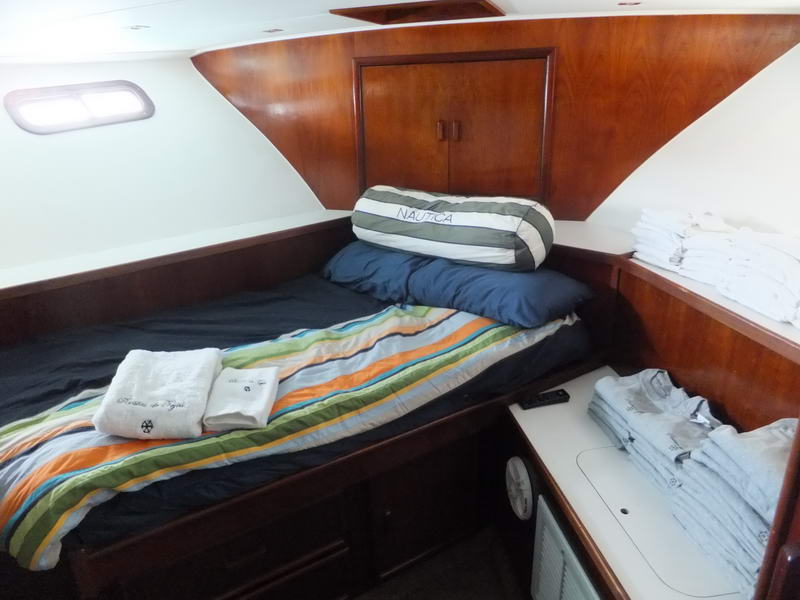 Cabin with a single berth made up with striped bedding and Nautica bolster pillow