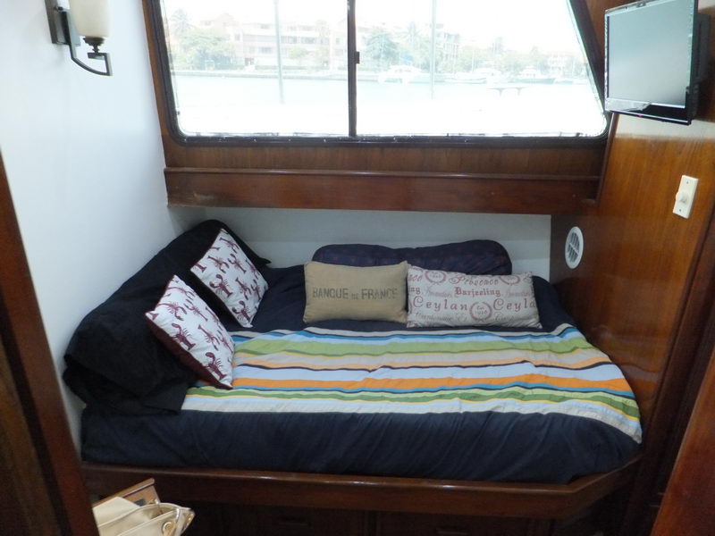 Cabin with double bed dressed in navy and striped bedding, glossy wood trim and a large window