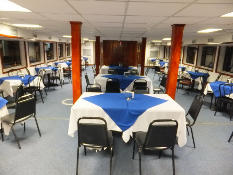Dining deck of the Princess boat set with blue-and-white linens on round tables between varnished columns