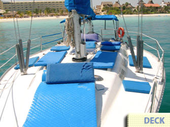 Proa del velero con colchonetas de sol y cojines azules anclado cerca de la Zona Hotelera de Cancún, renta privada