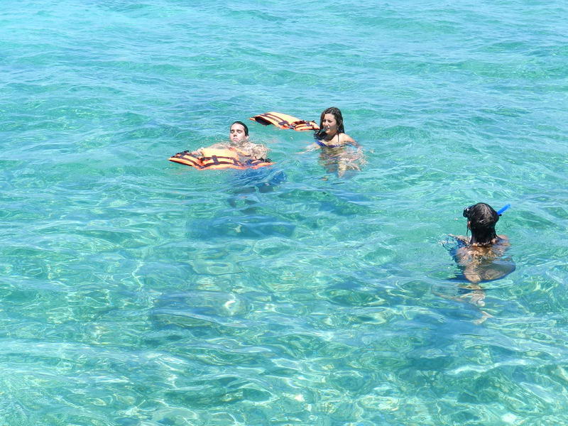 Passengers snorkeling with life jackets in crystal-clear Caribbean water on Cancun sailboat charter tour Isla Mujeres