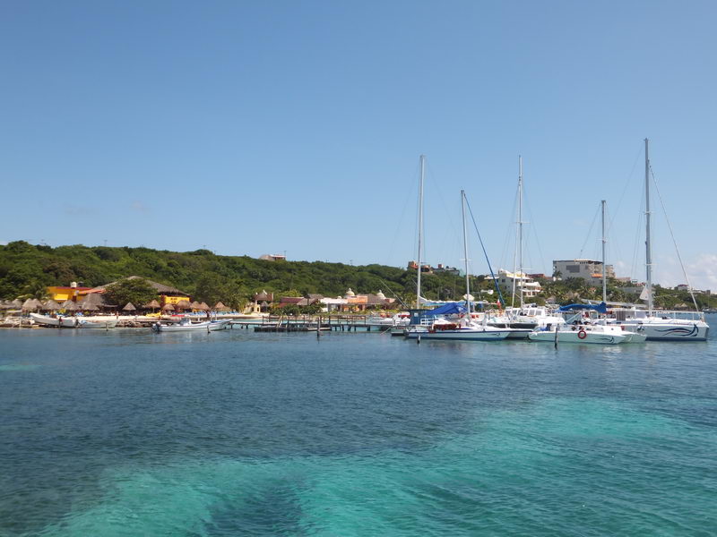 Sailboats and catamarans docked at Isla Mujeres marina with crystal turquoise water, lush hillside backdrop, Cancun sailing charter stop" loading="lazy" decoding="async">sailing tour Cancun" loading="lazy" decoding="async">sailing tour
