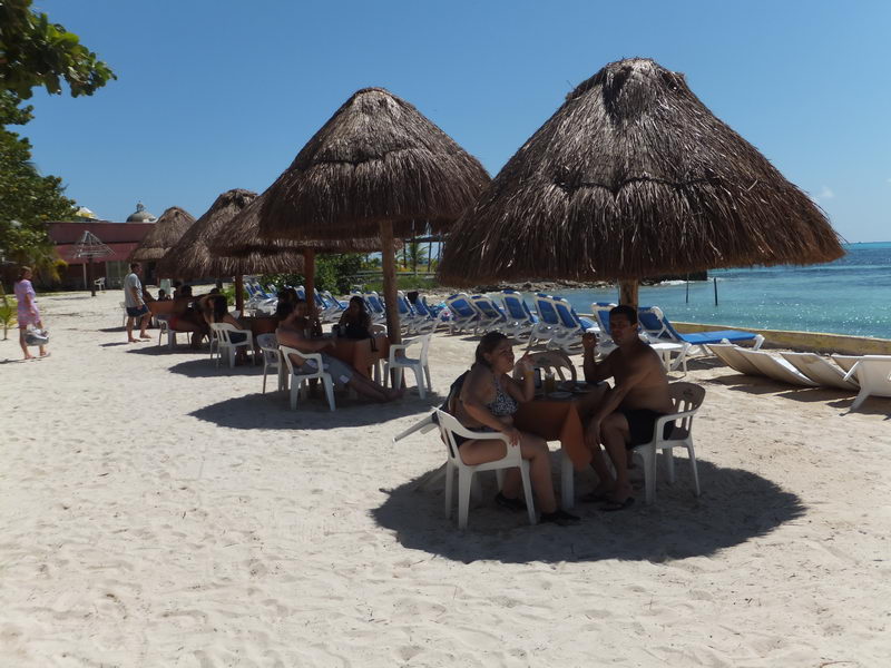 Palapa umbrellas and beach club tables on white sand at Isla Mujeres, lunch stop of the Samba catamaran tour from Cancun