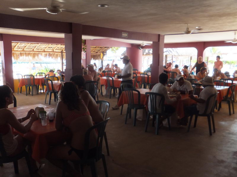 Tour guests dining at the open-air beach club restaurant on Isla Mujeres during the Samba catamaran day trip from Cancun