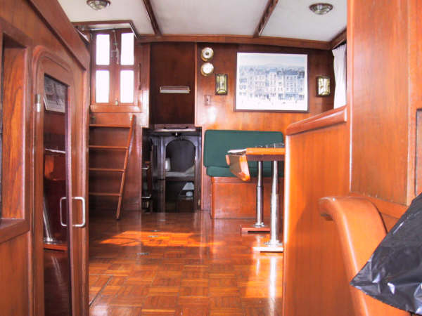 Warm wood-panelled interior salon of the Sandralyn yacht with parquet floor, dining settee and ladder to the cabins