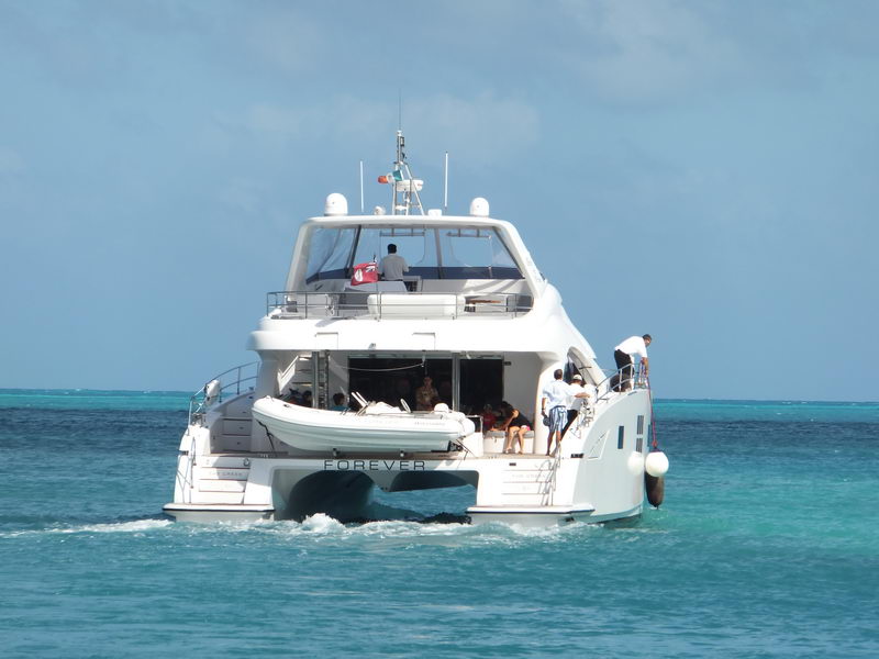 Stern view of the 66 ft Sunreef catamaran Forever cruising the Caribbean with guests and Williams tender, yacht charter Cancun