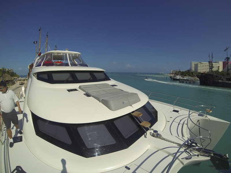 Foredeck sun pad and panoramic helm windows of the 66 ft Sunreef catamaran overlooking Cancun's turquoise lagoon, luxury charter
