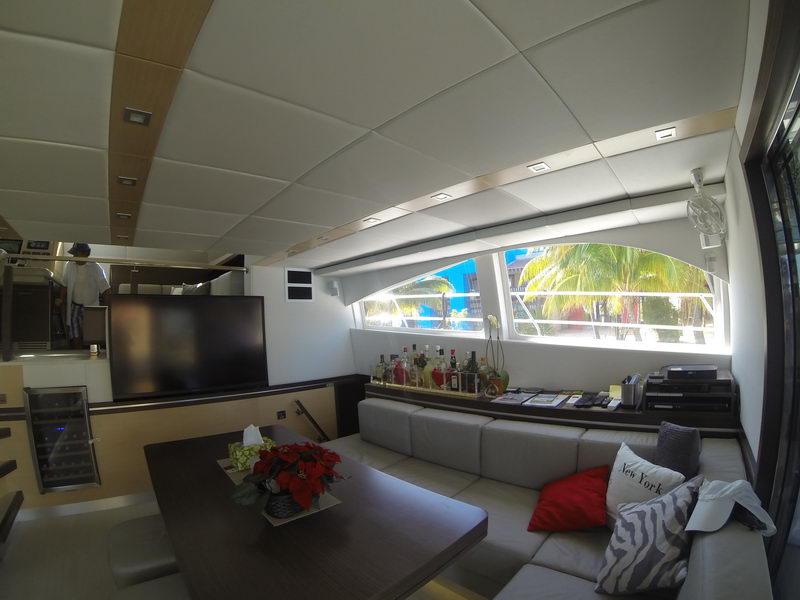Salon lounge of the 66 ft Sunreef catamaran with L-shaped sofa, dining table and palm views through panoramic windows, Cancun