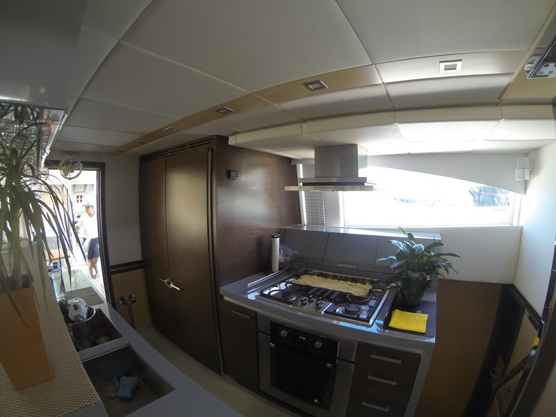 Modern galley of the 66 ft Sunreef power catamaran with gas range, oven and stainless hood, luxury yacht charter Cancun