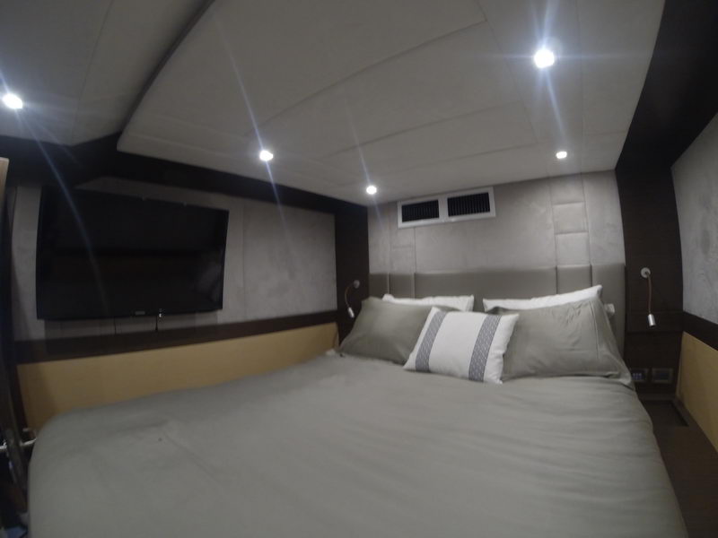 Master cabin of the 66 ft Sunreef catamaran with queen bed, suede headboard and wall-mounted TV, Cancun yacht rental