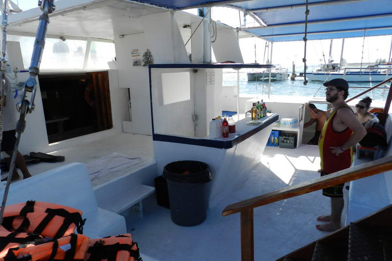 Shaded deck and open bar of the Tahuna catamaran with life jackets stacked, ready for a group sailing and snorkeling tour at Maroma Playa del Carmen